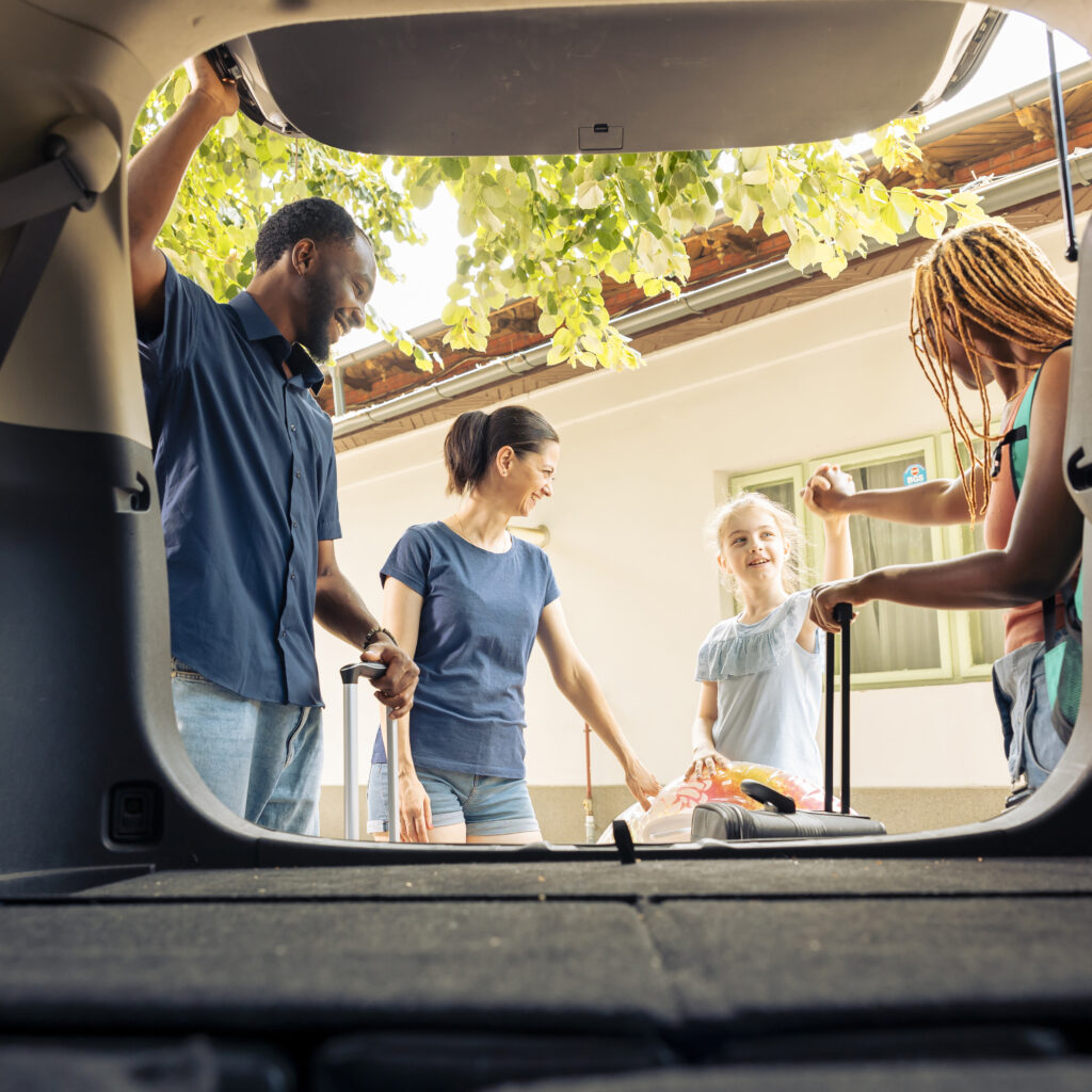 Mixed family and friends travelling on vacation with vehicle, going on summer holiday. Little girl with mother and young couple leaving with automobile on road trip journey, adventure.