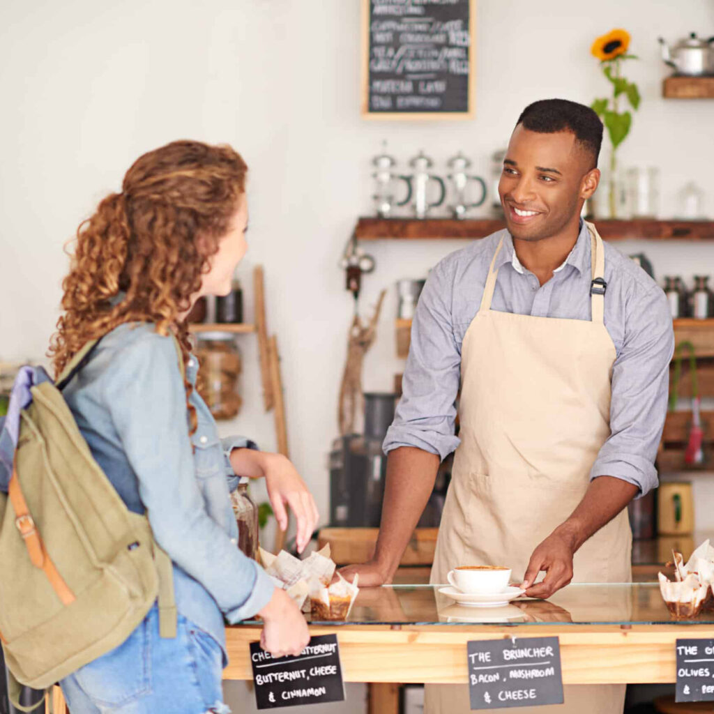 man working at a coffee shop talking to a woman customer
